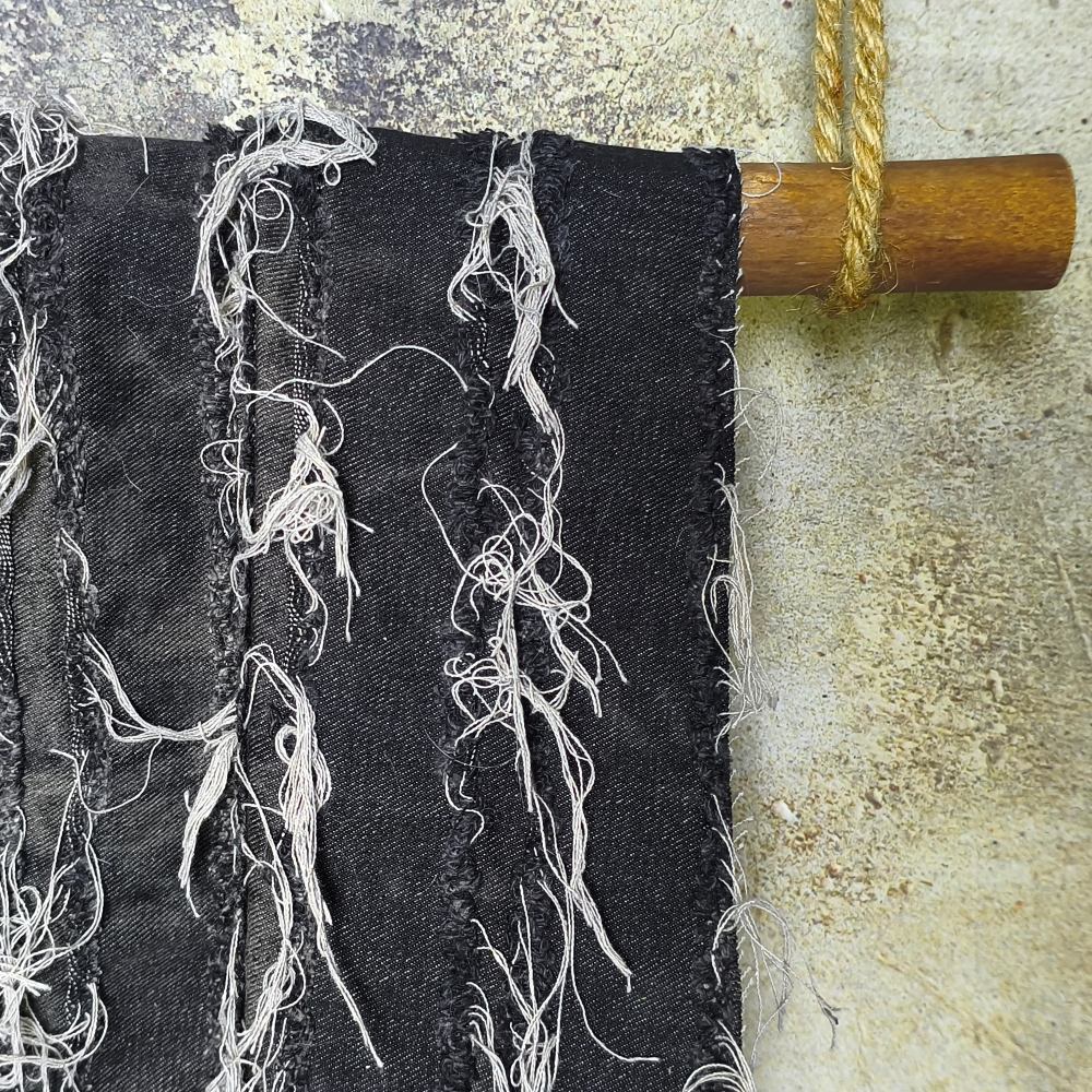 Black washed tie-dye denim fabric with horizontal stripes and fringed edges