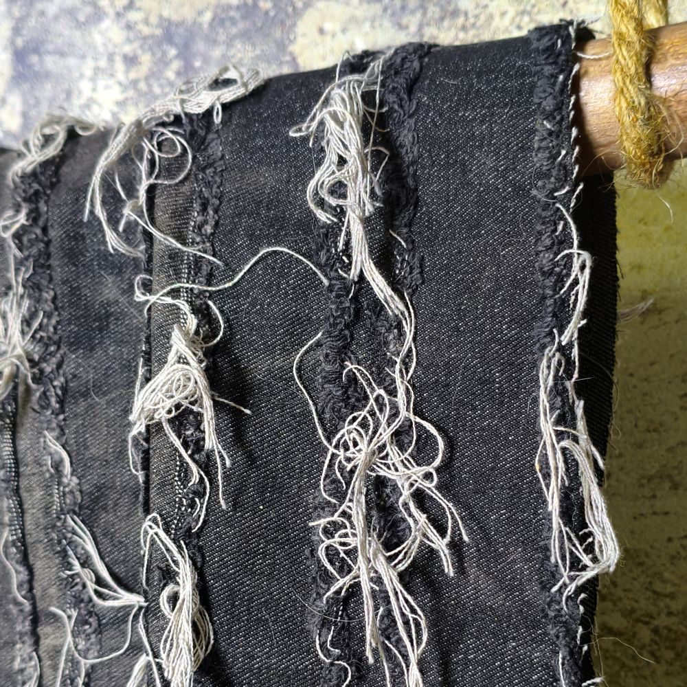 Black washed tie-dye denim fabric with horizontal stripes and fringed edges